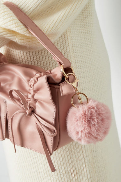Pink Puffy Ball Keyring hanging from a dusty pink handbag